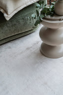 Angled lifestyle view of the Alchemy Oat White Rug under a coffee table in a contemporary bedroom suite